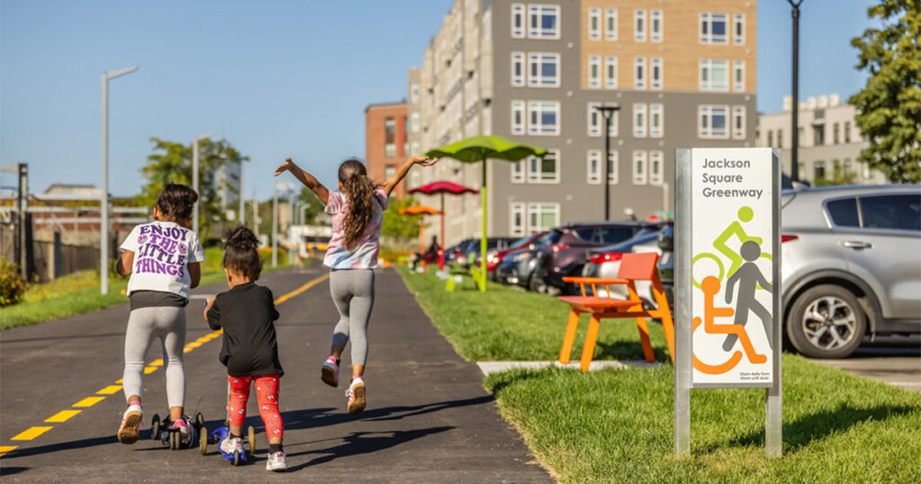 Three children traveling down a multi-use path called the Jackson Square Greenway