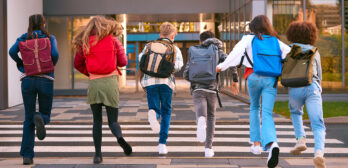 Gruop of 6 students running away from camera towards school
