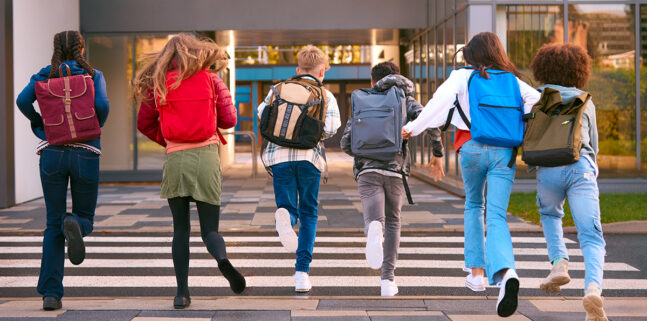 Gruop of 6 students running away from camera towards school